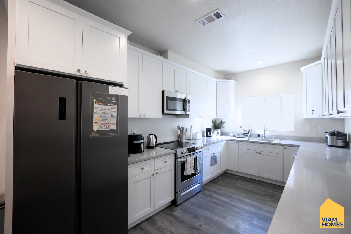 A furnished kitchen and dining area at VIAM Homes with designated fridge space and cabinet storage